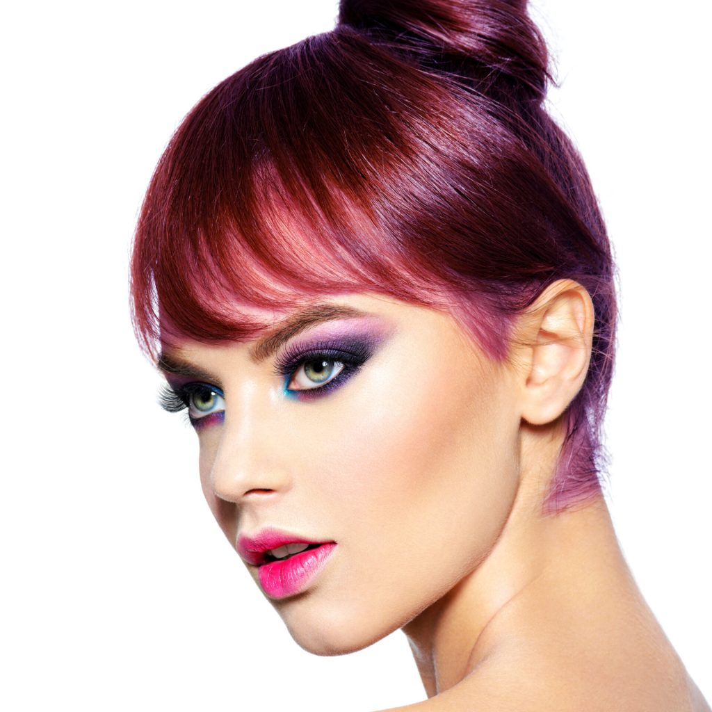Beautiful woman with bright professional make-up. Closeup face of a beautiful woman with bright vivid makeup. Fashion model with creative eye makeup - isolated on white. Girl with a ginger hair. Short hairstyle with fringe